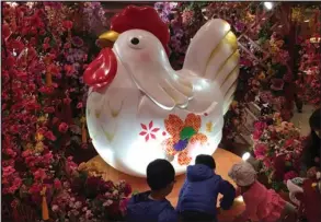  ?? ROY LIU / CHINA DAILY ?? Children play in front of a rooster statue before the coming Year of the Rooster at a shopping mall in Kowloon Bay.