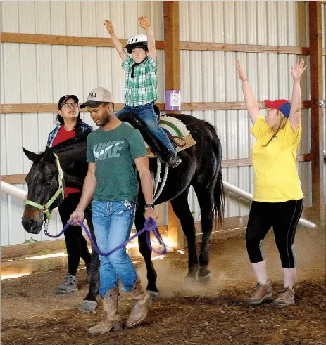  ?? Emily Jessen/Special to the Herald-Leader ?? Courage Therapeuti­c Riding Center volunteers help Dalton Reaves, 5, with his riding lesson. While riding, Reaves played games that helped him memorize his math facts.