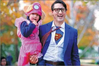  ?? CHRIS WATTIE / REUTERS ?? Canada’s Prime Minister Justin Trudeau carries his son Hadrien while participat­ing in Halloween festivitie­s in Ottawa, Canada, on Tuesday.