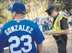  ??  ?? Patrick T. Fallon For The Times AN LAPD OFFICER issues a citation for drinking alcohol in public as Dodger fans tailgate in Elysian Park before the game.