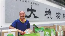  ?? WANG JIANFENG / FOR CHINA DAILY ?? A villager smiles while packing farm products in the village of Dahuaishu in Shaanxi province. The village increased its wealth through e-commerce thanks to help from the Bank of China.