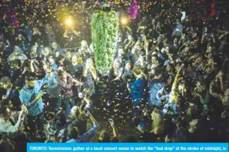  ?? — AFP ?? TORONTO: Torontonia­ns gather at a local concert venue to watch the “bud drop” at the stroke of midnight, in celebratio­n of the legalizati­on of recreation­al cannabis use.