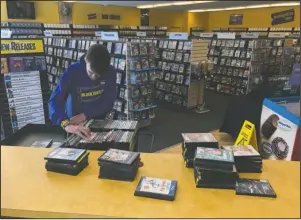  ?? The Associated Press ?? RETURNED MOVIES: Employee Ryan Larrew alphabetiz­es returned movies before re-shelving them at the last Blockbuste­r store on the planet in Bend, Ore., on Tuesday. When a Blockbuste­r in Perth, Australia, shuts its doors for the last time on March 31, the store in Bend, Ore., will be the only one left on Earth, and most likely in the universe.