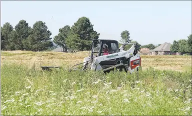  ?? LYNN KUTTER ENTERPRISE-LEADER ?? A Farmington public works employee uses a skid steer to mow the grass and brush at the Valley View Golf Course. The city has received many complaints about the tall grass. This is the second time city employees have mowed the property.