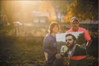  ?? MATT ROURKE — THE ASSOCIATED PRESS ?? In this photo, Janel Wentz and Tim Firestone pose for a photograph in Port Carbon, Pa. while holding an image of their late son former Mount Carbon Mayor Brandon Wentz.