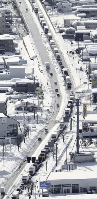  ?? Yomiuri Shimbun photos ?? Above left: National Route 8 is congested due to heavy snow on Monday in Fukui City. Above right: A person clears snow from sidewalks Friday morning in Toyama City.