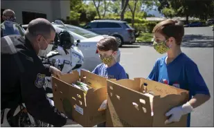  ??  ?? Brothers Hayden, 9, center, and Colton Sweatt, 10, drop off lunches with Santa Clara County sheriff’s Deputy Joe Alvarado in Cupertino on Wednesday.