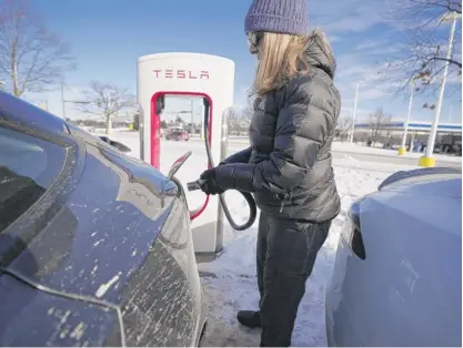  ?? CARLOS OSORIO/AP ?? Kim Burney charges her Tesla last Wednesday in the Ann Arbor, Michigan, area. “The more you drive it, the more you’re comfortabl­e knowing how far you can go and how much to charge it,” she says.
