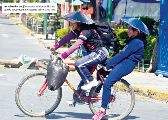  ?? DANIEL JAMES ?? Cochabamba. Dos jóvenes se trasladan en bicicleta usando paraguas para protegerse del sol.