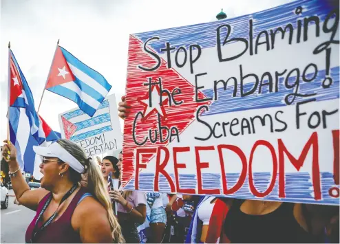  ?? EVA MARIE UZCATEGUI / AFP VIA GETTY IMAGES ?? People hold Cuban flags and placards at a Miami protest on Friday showing support
for Cubans demonstrat­ing against their government.