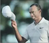  ?? Jason Getz Atlanta Journal-Constituti­on ?? TIGER WOODS TIPS his cap as he approaches the 18th green. He made the cut by two shots.