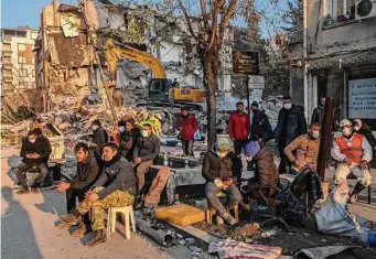  ?? Bernat Armangue/Associated Press ?? People sit next to a destroyed house as they wait for the bodies of friends and family members to be pulled from the rubble after an earthquake in Antakya, southeaste­rn Turkey, om Monday.