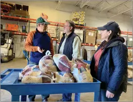  ?? COURTESY OF LIGHTHOUSE ?? Sen. Gary Peters, D-Michigan, center, and his wife, Colleen, speak with a Lighthouse staff member as they help pack boxes of food for Thanksgivi­ng.