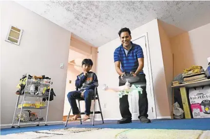  ?? KENNETH K. LAM/BALTIMORE SUN ?? Mohan Shahi flies a small drone as his son Swornim looks on in the basement of their new home. He is being trained as a drone pilot while working at an Amazon distributi­on center. The family bought a home in Elkridge about a month ago.