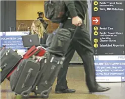  ?? — AP ?? SEATTLE: Asti Gallina (center) a volunteer law student from the University of Washington, works at a station near where passengers arrive on internatio­nal flights at SeattleTac­oma Internatio­nal Airport in Seattle. Gallina was volunteeri­ng with the...