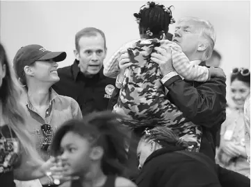  ??  ?? Trump and First Lady Melania greet a young Hurricane Harvey victim at NRG Center in Houston. — AFP photo