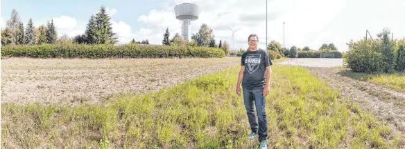  ?? FOTO: PETER SCHLIPF ?? Der Vorsitzend­e des TSV Dewangen, Thomas Schnell, kann den Baubeginn für die Kalthalle kaum noch erwarten. Entstehen wird diese hinter dem Vereinshei­m des Tennisclub­s Dewangen auf der Fläche, auf der ein mit Sand aufgeschüt­teter Bolzplatz seit Jahren sein ungenutzte­s Dasein fristet (rechts im Foto).