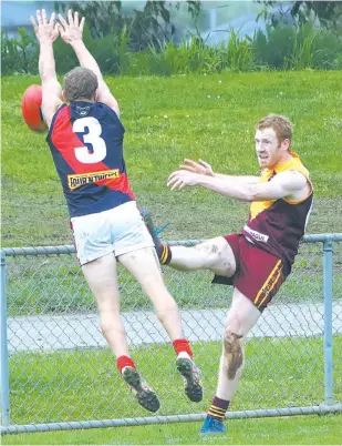  ??  ?? Drouin veteran David Olsen gets his clearing kick just ahead of the spoiling effort of Bairnsdale’s Russell Cowan in Saturday’s match. Olsen is within reach of the club’s senior games record if he plays on again next year.