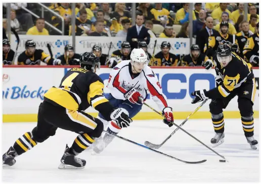  ??  ?? Washington Capitals left wing Andre Burakovsky (65) skates with the puck between Pittsburgh Penguins defenseman Justin Schultz (4) and center Evgeni Malkin (71) during the third period in Game 6 of the second round of the Stanley Cup Playoffs at PPG...