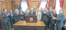  ?? MARK WALLHEISER/THE ASSOCIATED PRESS ?? Flanked by Florida legislator­s and family members of the Parkland school shooting victims, Florida Gov. Rick Scott signs a new gun-control law.