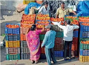  ?? — AFP ?? Traders and vendors negotiate prices of tomatoes at a wholesale market in Hyderabad. Distributo­rs and dealers have stopped fresh purchases and are focused on offloading old stock.