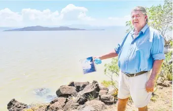  ??  ?? Murray Roberts, 69, who has lived on the shores of Lake Bogoria much of his life, like his father before him, is pictured in his compound holding an old photo of his sons jumping off a cliff face into the lake from the edge that is now that is now submerged under a few metres of the rising lake waters near Marigat, Baringo county on the Kenyan Rift Valley.