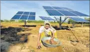  ?? AFP ?? A farmer works near solar panels installed in the field to help pump water for irrigation purposes, in Gujarat’s Dhundi.