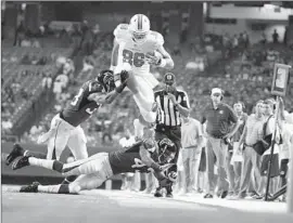  ?? David Goldman Associated Press ?? DOLPHINS TIGHT END Kyle Miller tries to hurdle Falcons defensive back Tay Glover-Wright, who gets help from Tyrell Johnson.