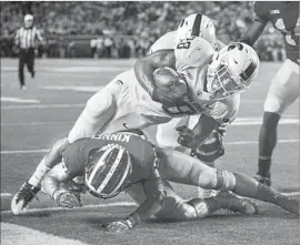  ?? Tony Ding Associated Press ?? MICHIGAN STATE’S Madre London dives over Michigan’s Tyree Kinnel to complete a 16-yard pass play for a touchdown in the second quarter at Ann Arbor.