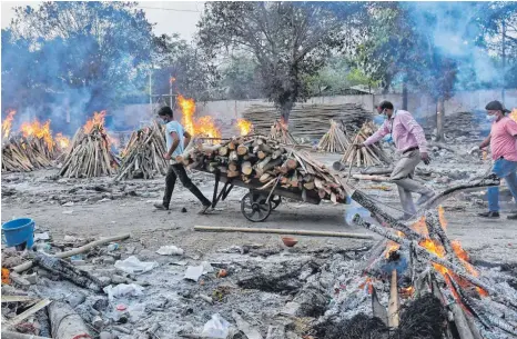  ?? FOTO: ISHANT CHAUHAN/DPA ?? Die Feuer der Krematorie­n am Stadtrand Neu Delhis brennen unablässig. Arbeiter müssen Tag und Nacht neues Holz herankarre­n.