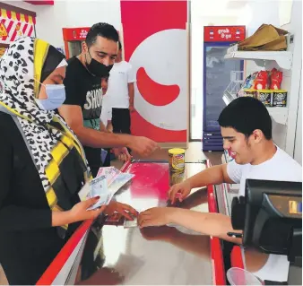  ?? Pawan Singh / The National ?? Omar Al Suwaidan, right, who had autism diagnosed at a young age, practises working as a cashier at a supermarke­t in Sanad Village Dubai