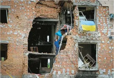  ?? EFREM LUKATSKY/AP ?? Residents take out belongings Saturday from their home ruined by shelling in Irpin, close to Kyiv, Ukraine.