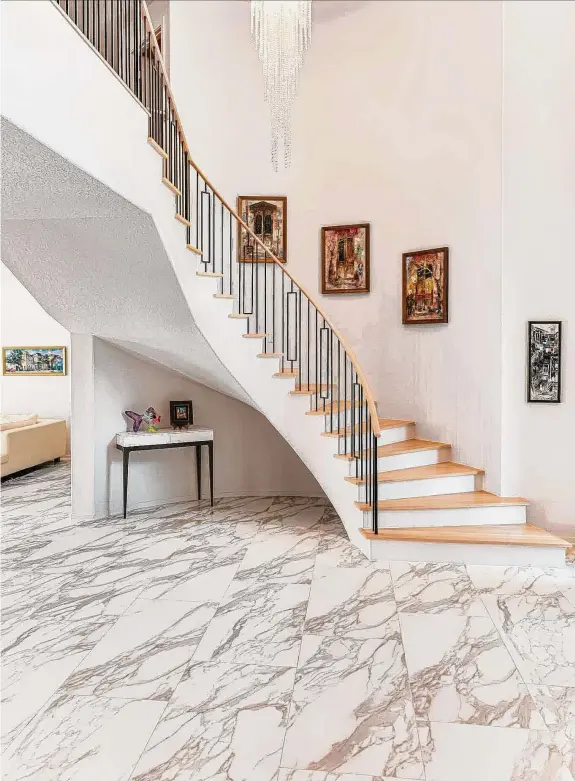  ?? Jeanette Berge ?? The new look for the foyer includes a staircase with an iron rail and white oak treads and handrail. The new showstoppe­r: a glittery chandelier.