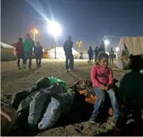  ?? AFP ?? A Palestinia­n girl sits as men build tents on the Gaza border. —