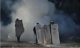  ?? Photograph: Luis Robayo/AFP/Getty Images ?? Demonstrat­ors take cover behind makeshift shields in Cali, Colombia, on 30 April.