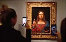  ??  ?? People take pictures with mobile phone at an oil painting by Atelier Leonardo da Vinci’s ‘Salvator Mundi’ (Version Ganay), during the opening of the exhibition ‘Leonardo da Vinci’, at the Louvre museum in Paris. — AFP