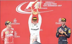  ?? JOE KLAMAR/AFP ?? Valtteri Bottas lifts the trophy after winning the Austrian GP as second-placed Sebastian Vettel (left) and Daniel Ricciardo look on yesterday.