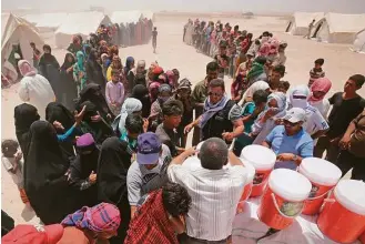  ?? Ahmad al Rubaye / AFP / Getty Images ?? Iraqis displaced from Fallujah line up Monday to collect aid distribute­d by the Norwegian Refugee Council at a newly opened camp where they are taking shelter in Amriyat al-Fallujah.