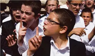  ?? Ariel Schalit / Associated Press ?? Ultra-Orthodox youth yell at a reporter covering the Jewish women’s prayer at the Western Wall.