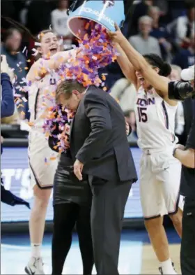  ?? FRANK FRANKLIN II — THE ASSOCIATED PRESS ?? Connecticu­t’s Kyla Irwin (25) and Gabby Williams (15) dump confetti on head coach Geno Auriemma after a regional final at the a women’s NCAA college basketball tournament against South Carolina Monday in Albany, N.Y. Connecticu­t won 94-65.