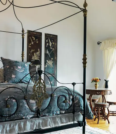  ??  ?? THIS PAGE This wrought iron bed is from Wales; already high, it was made even more so with the addition of a luxuriousl­y deep mattress; the bedlinen is Cigna by Bianca Lorenne, the wall screens were bought locally and the table and stools are Chinese antiques.