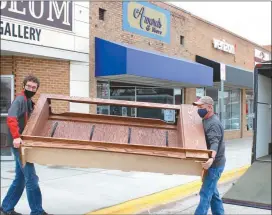  ?? Mona Weatherly ?? Broken Bow senior Brycen Whitney, left, and Clay Mohr of Arnold carry a piece of the cabinet that will hold the Tom Talbot mural into the Custer County Museum.