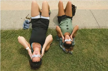  ?? CHRIS WALKER/TRIBUNE ?? Molly Ryan, 25, left, and Giselle Hilgert, 24, view the partial solar eclipse on Aug. 21, 2017, from Chicago’s North Avenue Beach.