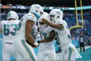  ?? LYNNE SLADKY — THE ASSOCIATED PRESS ?? Miami Dolphins safety Jason McCourty (30) and wide receiver Jaylen Waddle (17) congratula­te wide receiver Mack Hollins (86) after Hollins scored a touchdown during the first half of an NFL football game against the New York Giants, Sunday, Dec. 5, 2021, in Miami Gardens, Fla.