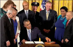  ?? AP/JACQUELYN MARTIN ?? President Barack Obama, surrounded by gay-rights supporters including Virginia Gov. Terry McAuliffe (third from right), signs executive orders in the East Room of the White House on Monday to protect gay employees from federal workplace discrimina­tion.