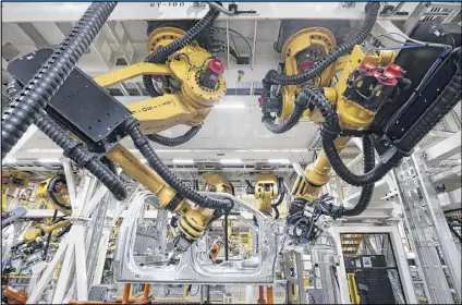  ?? AP 2014 ?? Robots put rivets on a 2015 Ford F-150 truck at the Dearborn Truck Plant in Dearborn, Mich. Cheaper robots will replace human workers in factories more quickly in the next decade, a report says.