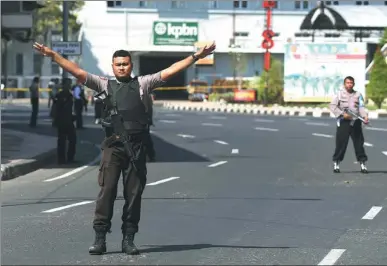  ?? ACHMAD IBRAHIM / ASSOCIATED PRESS ?? An officer gestures as authoritie­s block a road outside police headquarte­rs following an attack in Surabaya, Indonesia, on Monday.