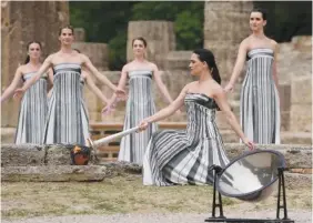  ?? AP PHOTO/THANASSIS STAVRAKIS ?? Actress Mary Mina lights a torch Tuesday during the official ceremony of the flame lighting for the Paris Olympics, at the Ancient Olympia site in Greece. The flame will be carried through Greece for 11 days before being handed over to Paris organizers April 26.