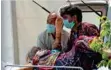  ?? AP, Reuters ?? ■
■
■
Top: A man reads a holy book before cremating his relative who died of Covid-19, in New Delhi, on Monday.
Above left: A Covid-19 patient waits inside a hospital in Noida. Above right: Relatives carry the body of a woman, who died from Covid-19, outside LNJP Hospital in New Delhi.