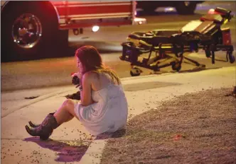  ?? The Associated Press ?? A woman sits on a curb at the scene of a shooting outside of a music festival along the Las Vegas Strip on Monday night.